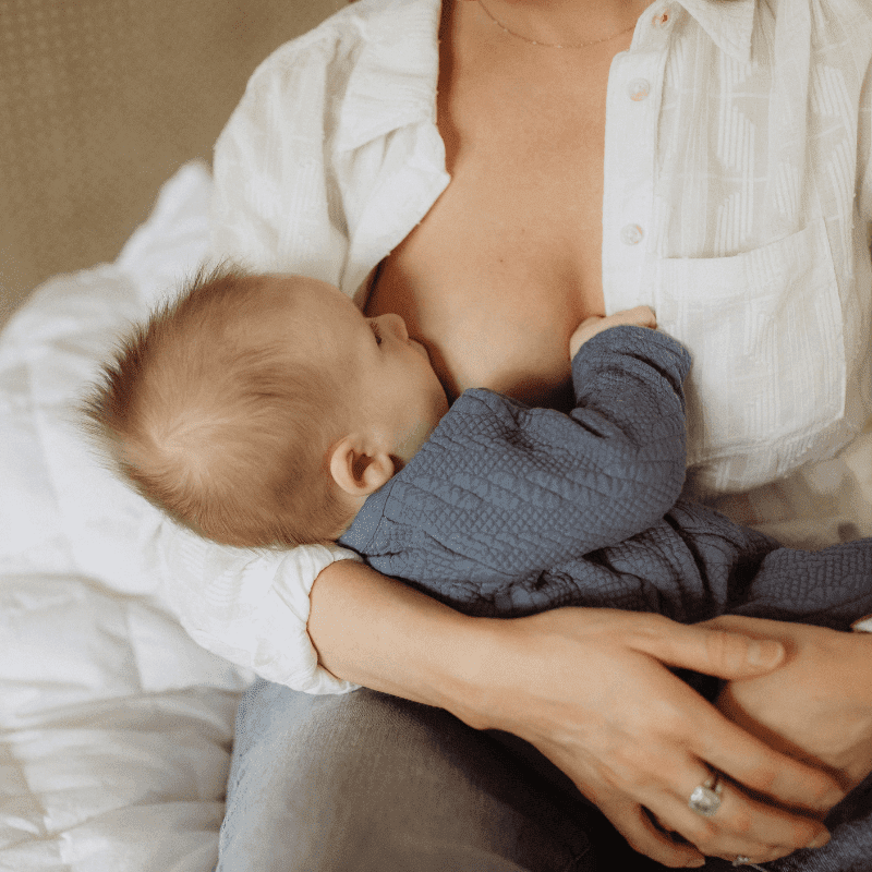 Moeder die borstvoeding geeft aan haar baby in een comfortabele houding, een natuurlijk en intiem moment van voeding en hechting.