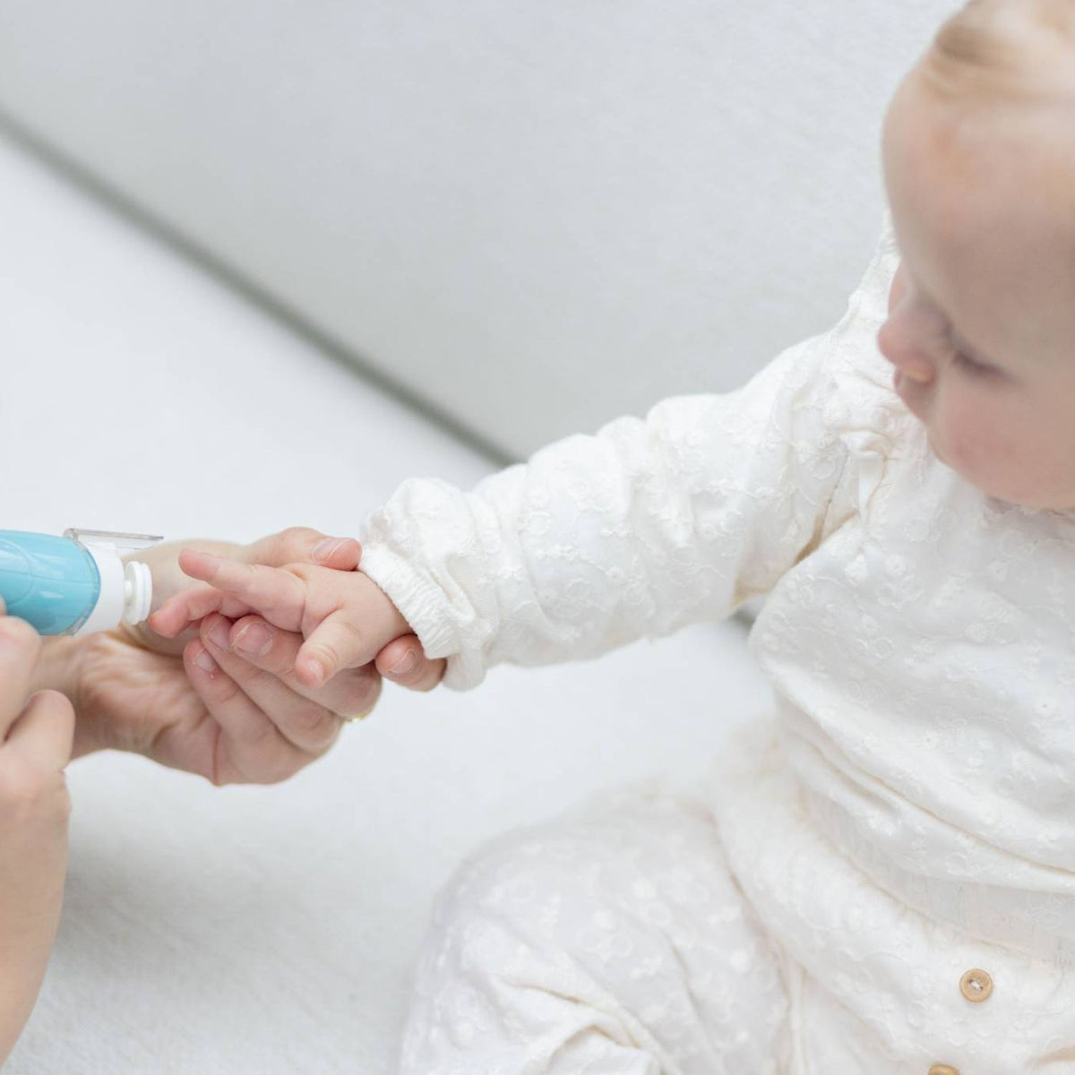 Een ouder gebruikt de Youha elektrische baby manicure set om voorzichtig de nagels van hun baby pijnloos en veilig te vijlen, met de lichte en ergonomische nagelvijl.