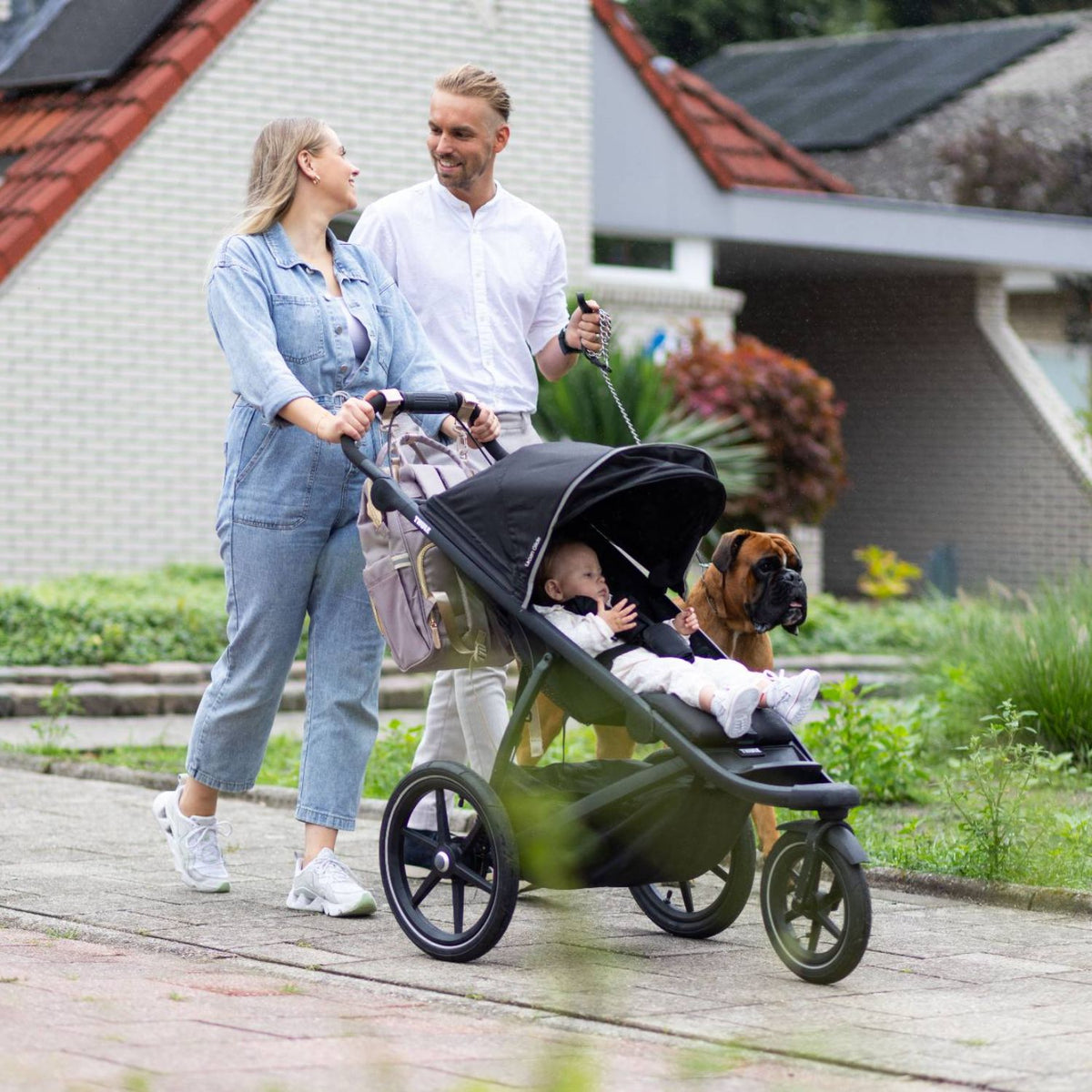 Gezin met baby gebruikt de Youha luiertas die gemakkelijk aan de kinderwagen hangt, voor praktisch gebruik onderweg.